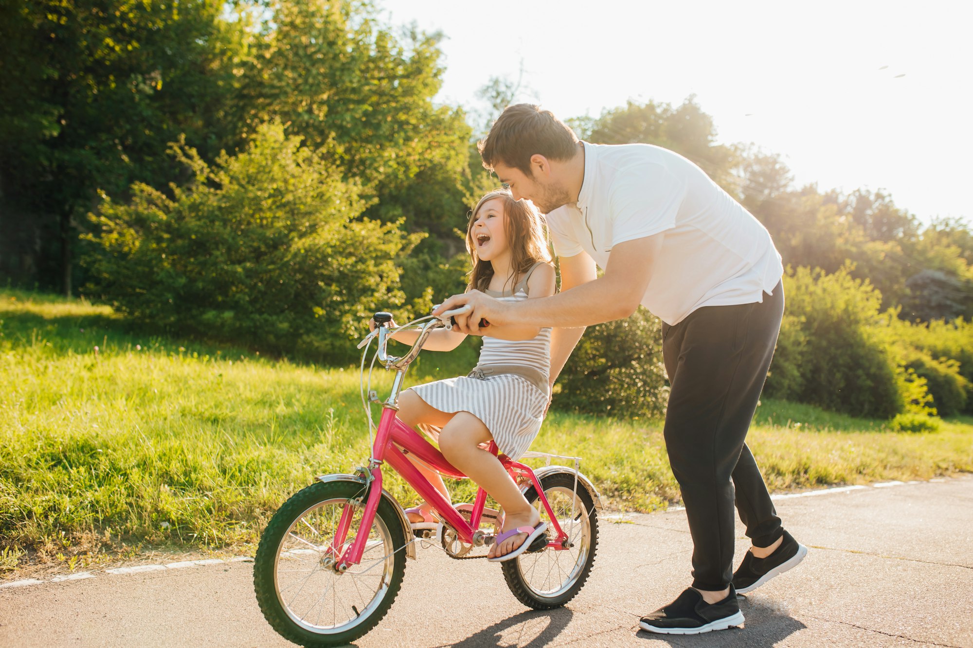 Little girl learning ride bicycle with father.